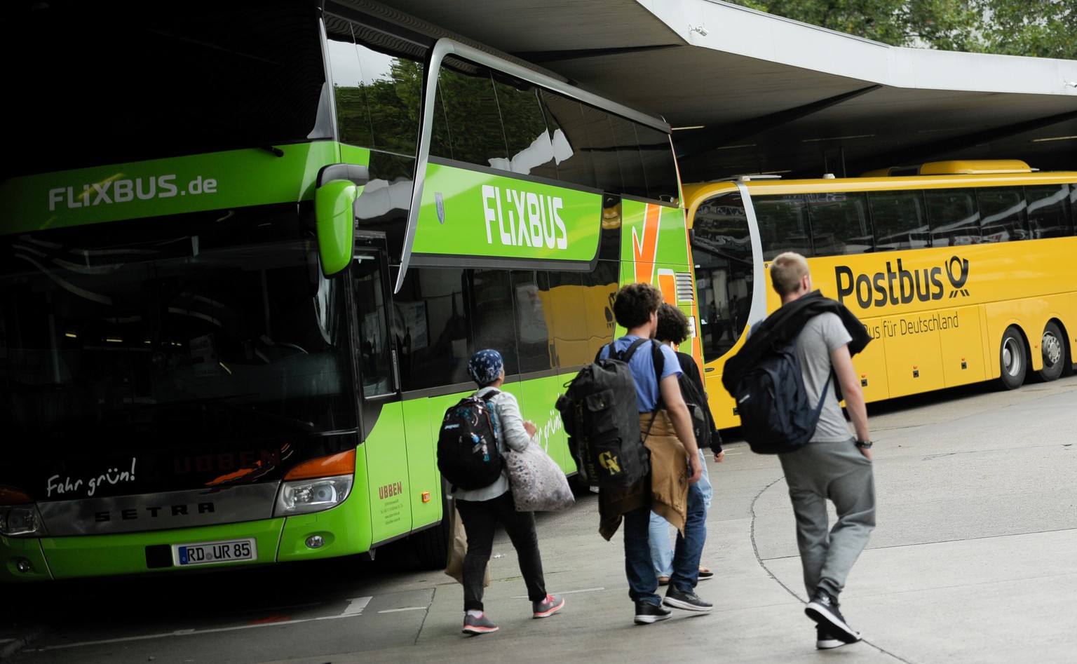 Passengers walk near Flixbus and Postbus busses at the main bus station (ZOB) in Berlin, Germany August 3, 2016. REUTERS/Stefanie Loos