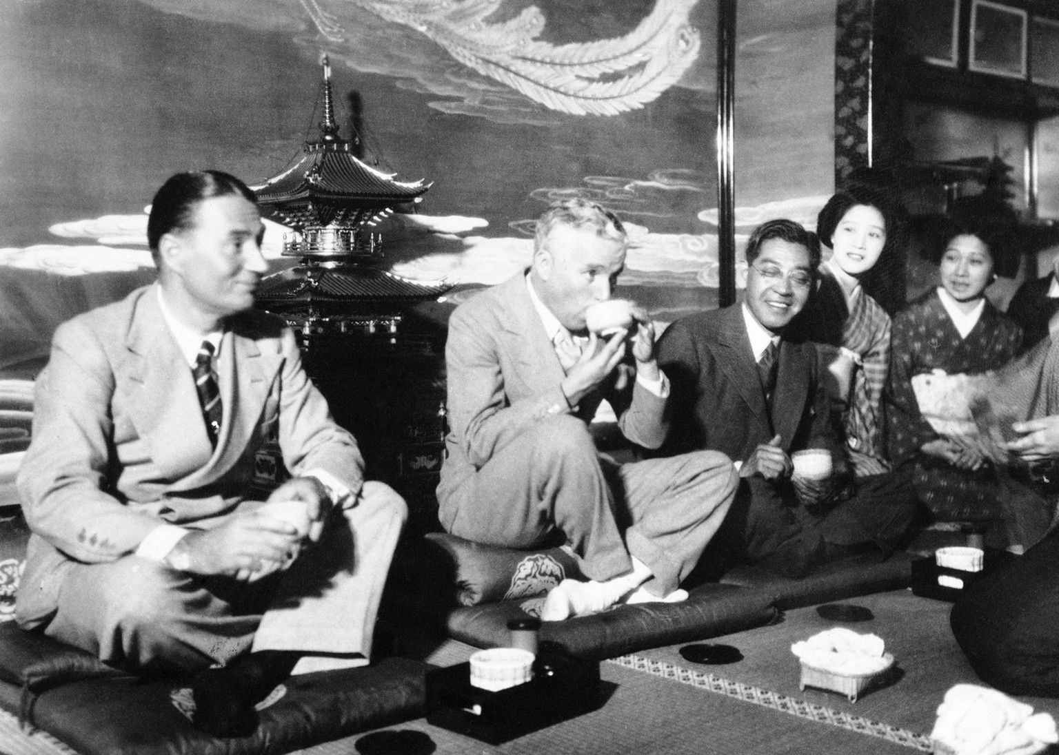 Charlie Chaplin sipping tea at a party in Tokyo on June 2, 1932, some what to the amusement of his admirers. His brother, Sydney, is at his right. (AP Photo)