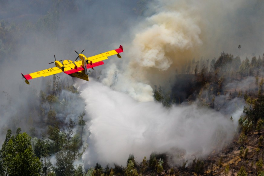 epa06035056 A Spanish Canadair fire fighting aircraft drops water over the Pedrogao Grande forest fire, in central Portugal, 18 June 2017. At least sixty two people have been killed in forest fires in ...