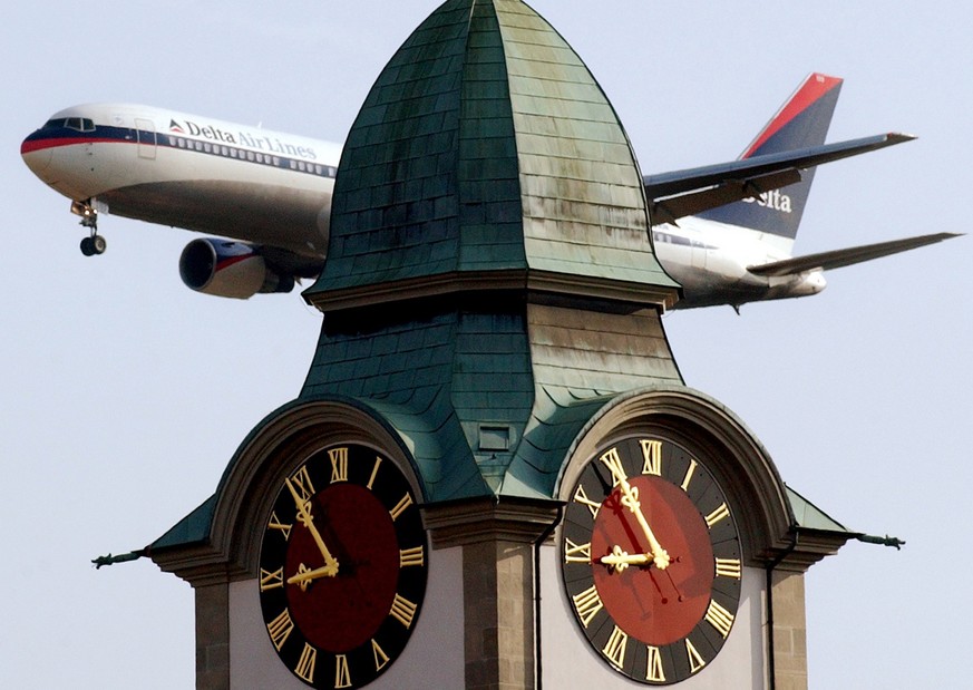 Eine Maschine der Fluggesellschaft Delta Airlines fliegt am Samstag, 29. Maerz 2003, am Turm der reformierten Kirche in Kloten vorbei. Kloten ist eine der leidtragenden Gemeinden in Bezug auf Fluglaer ...