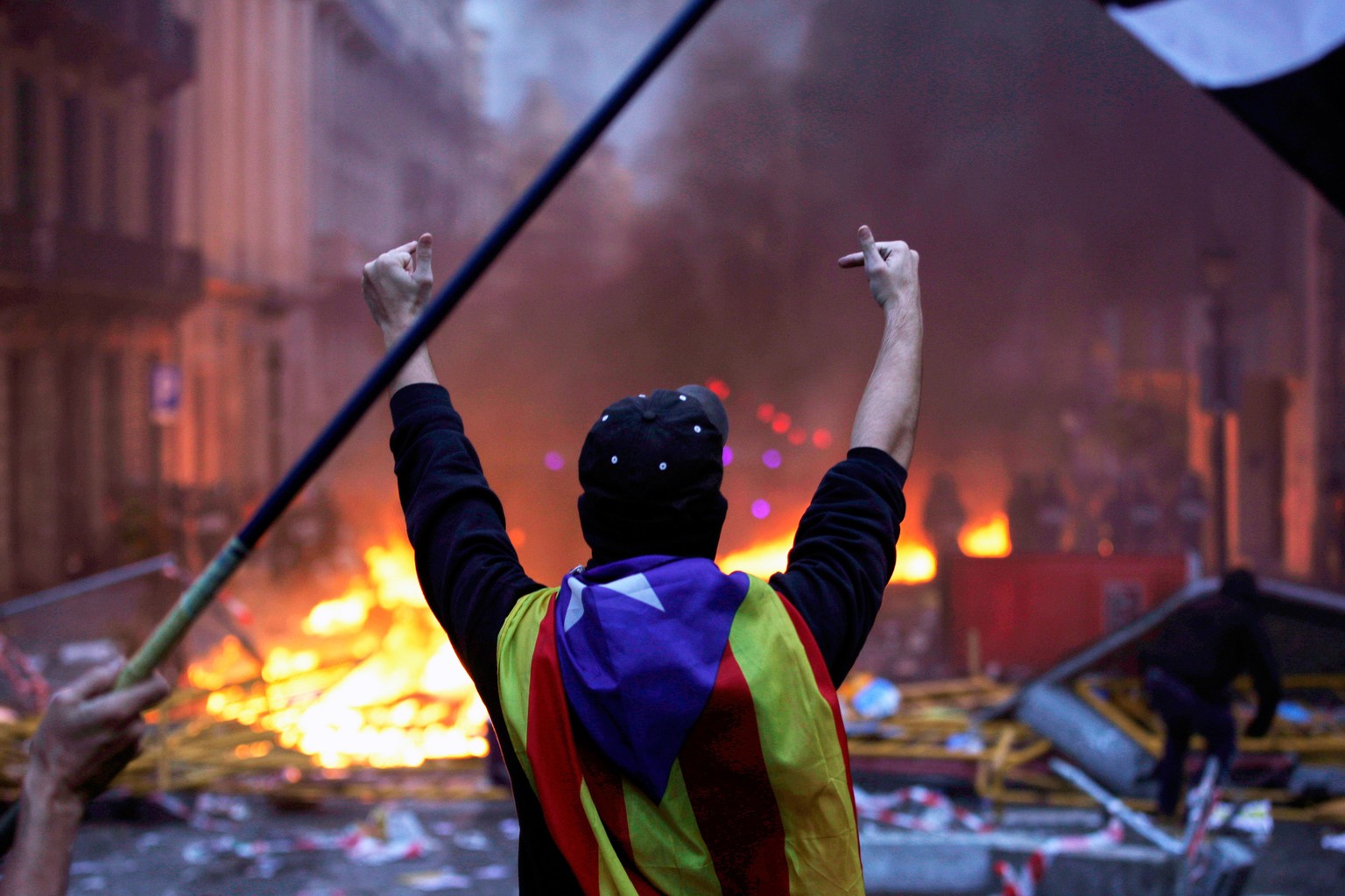 epa07930973 A protester gestures wearing a &#039;Estelada&#039; flag, the unofficial flag typically flown by Catalan independence supporters, during incidents with police as thousands of people take p ...