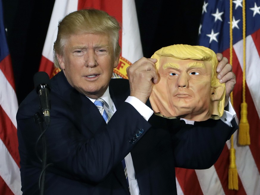 Republican presidential candidate Donald Trump holds up a Donald Trump mask during a campaign speech, Monday, Nov. 7, 2016, in Sarasota, Fla. (AP Photo/Chris O&#039;Meara)