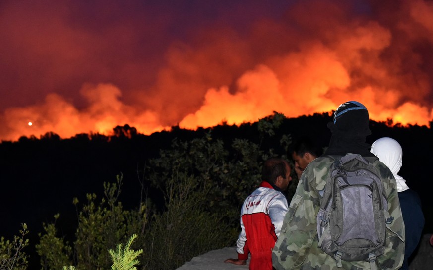 epa06093686 Tourists watch a forest fire from a church next to a monastery in the Lustica Peninsula near Tivat, Montenegro, 17 July 2017. At least 100 tourists have been forced to evacuate from the Lu ...