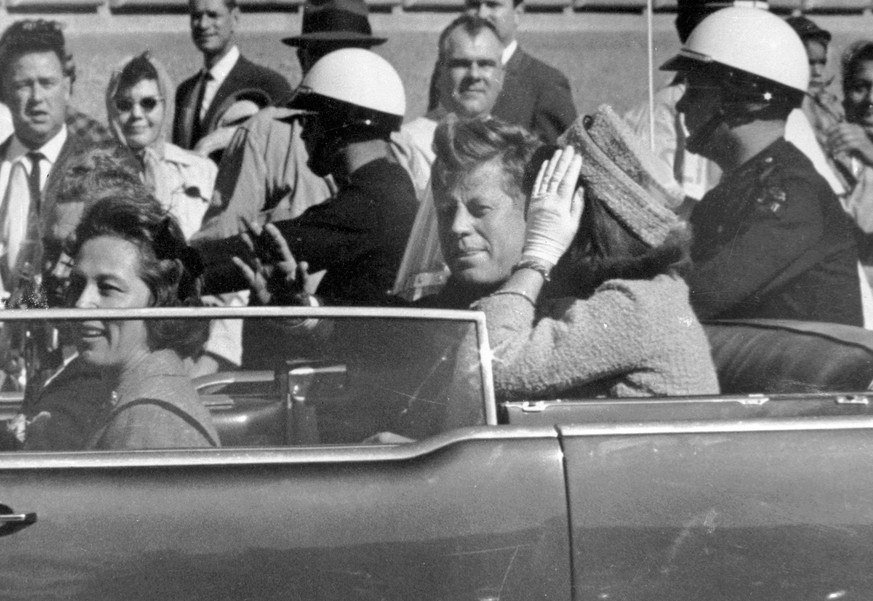FILE - In this Nov. 22, 1963 file photo, President John F. Kennedy waves from his car in a motorcade approximately one minute before he was shot in Dallas. Riding with Kennedy are First Lady Jacquelin ...