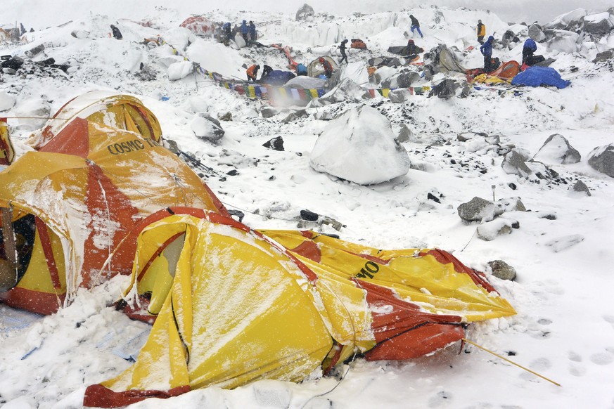 In this Saturday, April 25, 2015 photo, climbers search through crushed tents for fellow climbers caught in an avalanche at a base camp on the Nepal side of Mount Everest. Set off by a magnitude 7.8 e ...