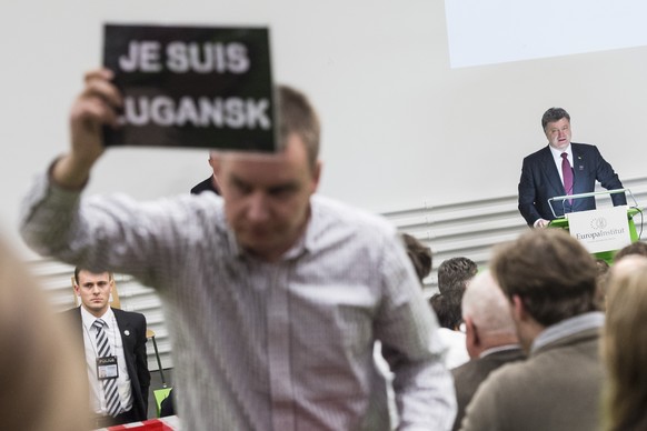 Ukrainian President Petro Poroshenko, background right, is interrupted by a demonstrator while giving a lecture within the scope of the Special Churchill Lecture 2015 at the Europe Institut of the Uni ...