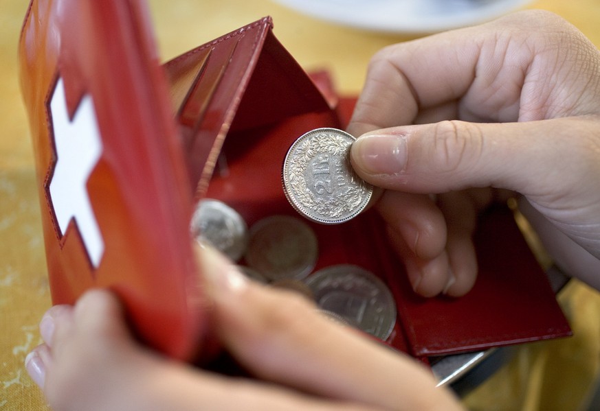 Eine Person nimmt am 24. Oktober 2005 in einem Restaurant im Hauptbahnhof Zuerich einen Zweifraenkler aus dem Portemonnaie. (KEYSTONE/Martin Ruetschi)

A person takes out a 2-franc-coin off a purse in ...