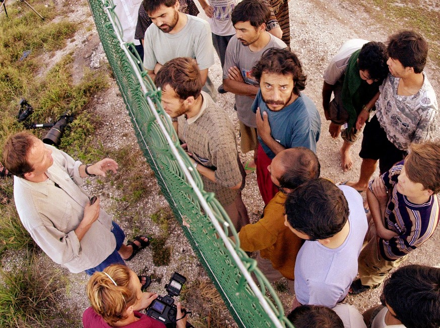 FILE - In this Sept. 19, 2001, file photo, refugees, right, gather on one side of a fence to talk with international journalists about their journey that brought them to the Island of Nauru. Human rig ...