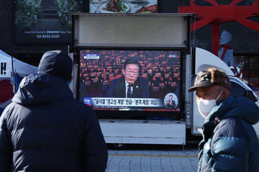 Nachrichten Linkding epa11761414 People watch a televised interview of opposition leader Lee Jae-myung after President Yoon Suk Yeol?s address to the nation, in Seoul, South Korea, 07 December 2024. South Korea's Pre ...
