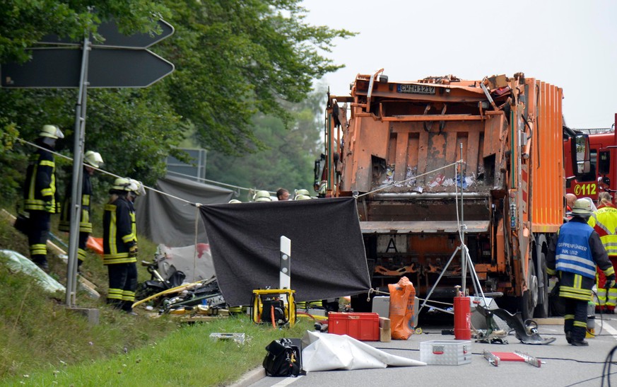 epa06137833 Members of fire department work at the scene of an accident involving a garbage truck and a car near Nagold, South-West Germany, 11 August 2017. The garbage truck overturned and fell on a  ...