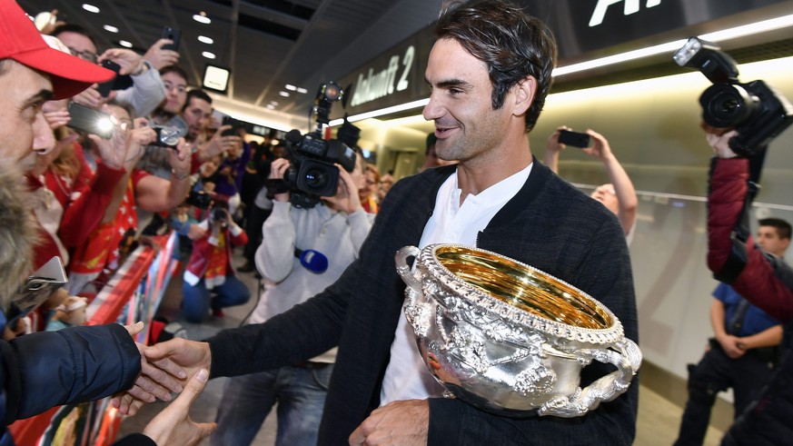 epa05762739 Swiss tennis player Roger Federer carries the Australian Open trophy and greets fans upon his arrival at Zurich Airport in Kloten, Switzerland, 31 January 2017. Federer won the men&#039;s  ...