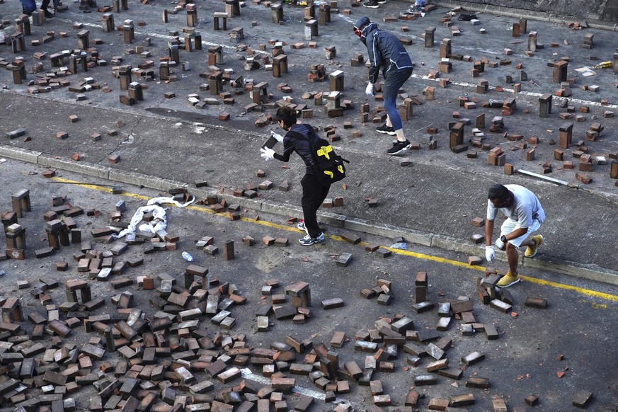 Protestors use bricks to barricade a road near the Hong Kong Polytechnic University in Hong Kong, Sunday, Nov. 17, 2019. A Hong Kong police officer was hit in the leg by an arrow Sunday as authorities ...
