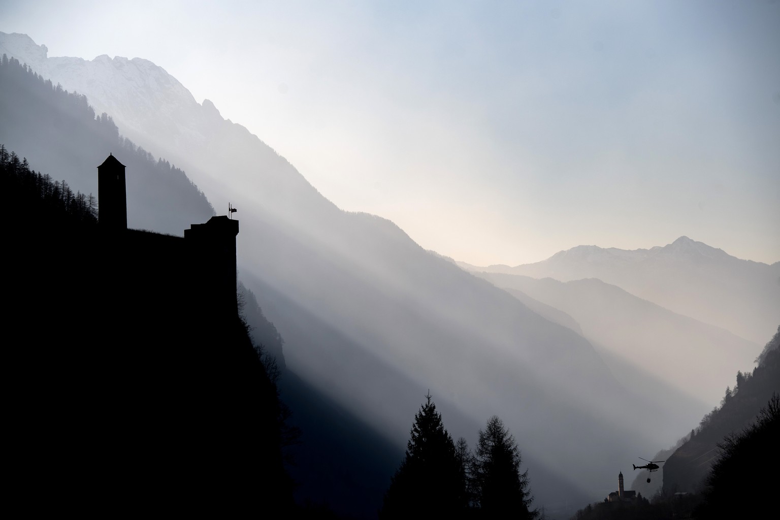 CAPTION ADDITION: PRECISES LOCATION --- A Swiss army Superpuma Helicopter flies near the church of Soazza, down right, and the castle of Mesocco, left, to discharge water over the forest fires near Me ...