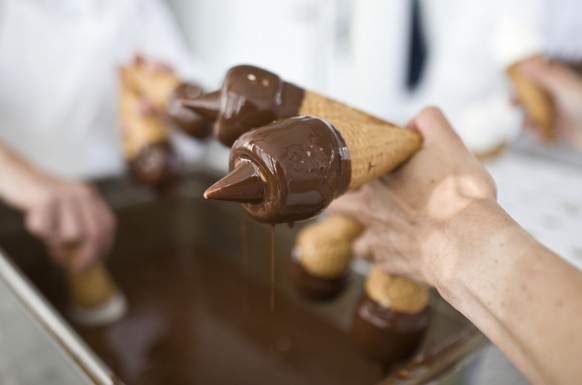 Employees of Swiss ice cream manufacturer Gasparini dip ice cream in liquid chocolate for the production of the classical vanille cornets, pictured on August 6, 2008 in Muenchenstein in the canton of  ...