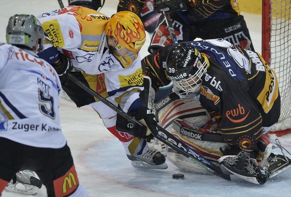 Die Zuger Domenico Pittis und Topskorer Linus Omark, von links, und der Berner Torhueter Marco Buehrer, rechts, kaempfen um den Puck im ersten Playoff-Halbfinalspiel der National League A zwischen dem ...