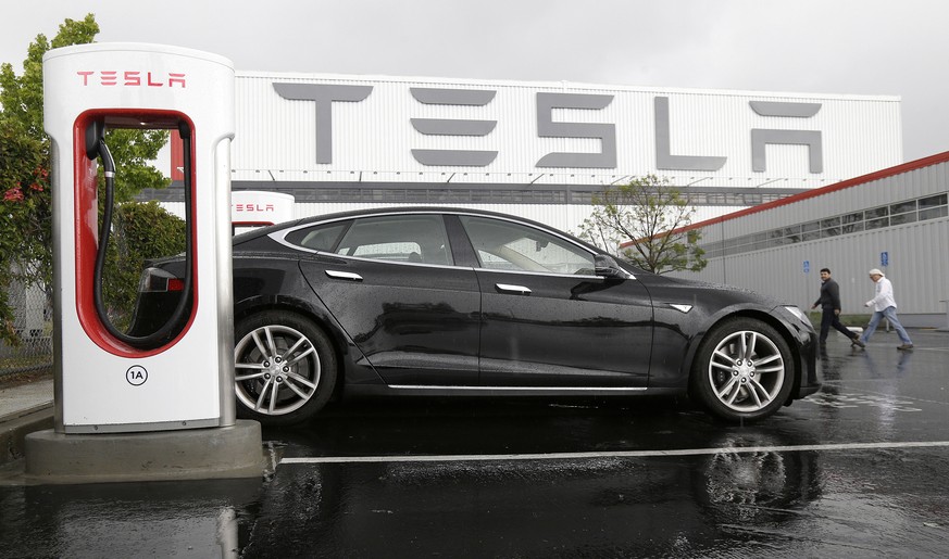 In this May 14, 2015 photo, a Tesla vehicle is parked at a charging station outside of the Tesla factory in Fremont, Calif. Tesla reports quarterly financial results on Wednesday, Aug. 5, 2015. (AP Ph ...
