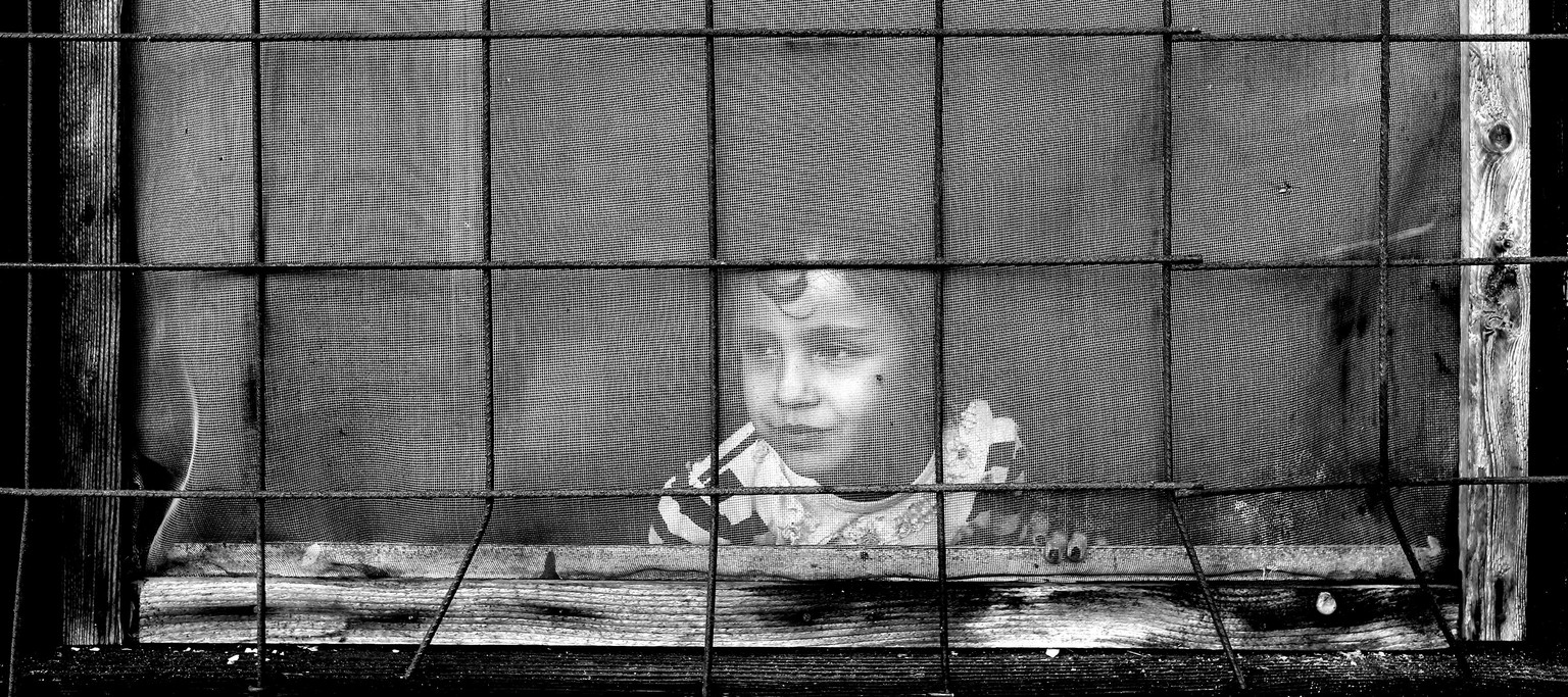 Serbien, in der Nähe von Belgrad, 2016: Ein Mädchen in einem Flüchtlingscamp schaut aus dem Fenster.