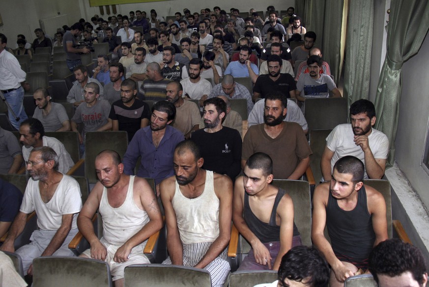 FILE - In this September 1, 2012 file photo, Syrian detainees who took part in anti-government protests sit in a courtroom before their release, in Damascus, Syria. Syrian intelligence agents grab civ ...