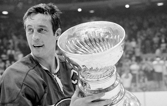 Montreal Canadiens team captain Jean Beliveau holds the Stanley Cup trophy after his team&#039;s 3-2 victory over the Chicago Black Hawks in the NHL playoff game in Chicago, Ill., Tuesday night, May 1 ...