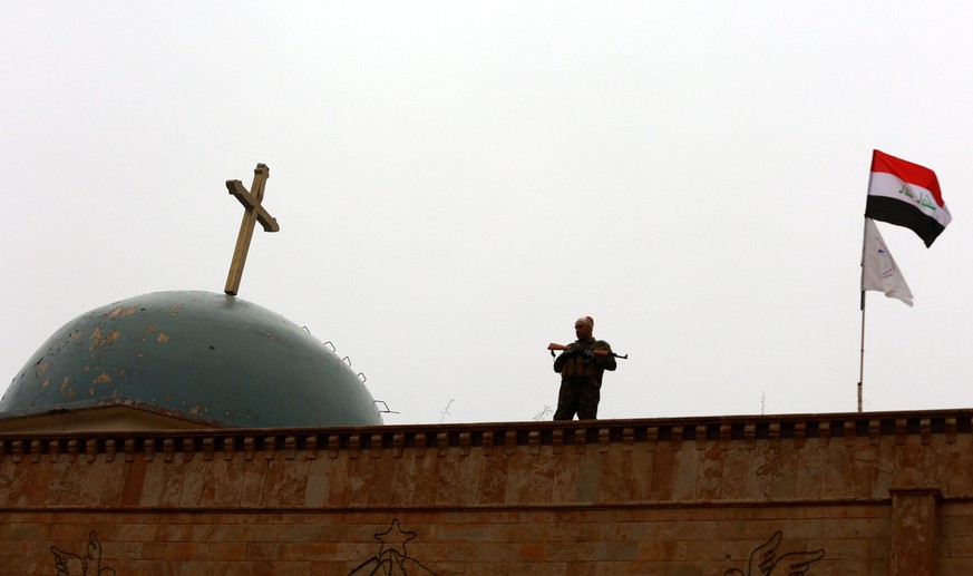 epa05688107 An Iraqi soldier stands guard during Christmas celebrations at the al-Tahira al-Kubra church in the formerly IS held town of al-Hamdaniya, some 13km east of Mosul, Iraq, 25 December 2016.  ...