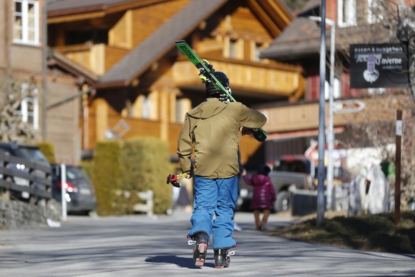 Ein Skifahrer traegt eine Skis am Donnerstag, 29. Dezember 2016 durch Adelboden. (KEYSTONE/Peter Klaunzer)