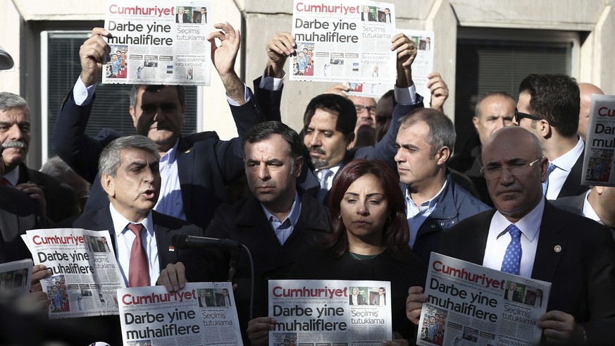 FILE - In this Oct. 31, 2016, file photo, Journalists and lawmakers hold a latest copy of Cumhuriyet newspaper outside its Istanbul headquarters after police detained chief editor Murat Sabuncu and tw ...