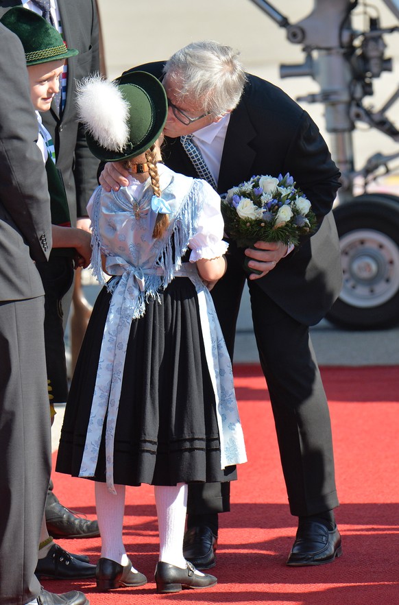 European Commission President Jean-Claude Juncker kisses a girl dressed in traditional Bavarian clothes during a welcoming ceremony after his arrival at the airport in Munich, southern Germany, Sunday ...