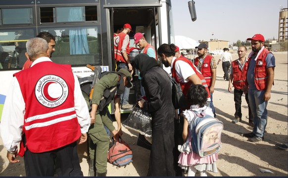 epa05512264 The Syrian Arab Red Crescent&#039;s staff assist people, who were evacuated, from the government-besieged city of Darayya on the southwestern countryside of Damascus, upon arrival at Herje ...