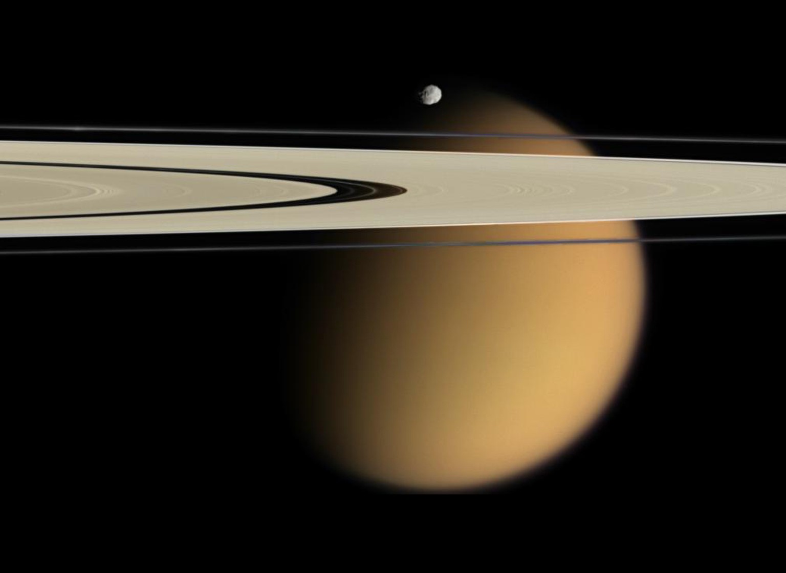 Von Smog eingehüllt: Saturnmond Titan, davor die Ringe des Saturn und der kleine Mond Epimetheus.&nbsp;