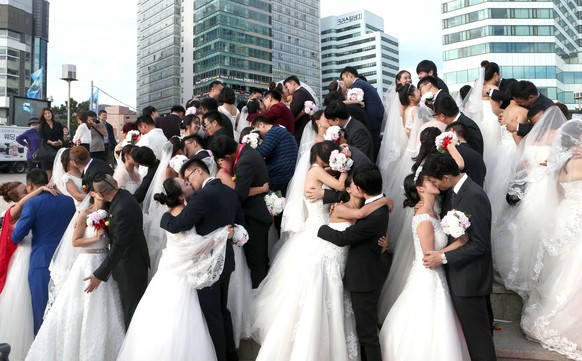 Chinese brides and grooms kiss during a group wedding ceremony on Haeundae Beach in Busan, southern South Korea, Monday, Oct. 26, 2015. Seventy-eight couples married on Monday during a promotional eve ...