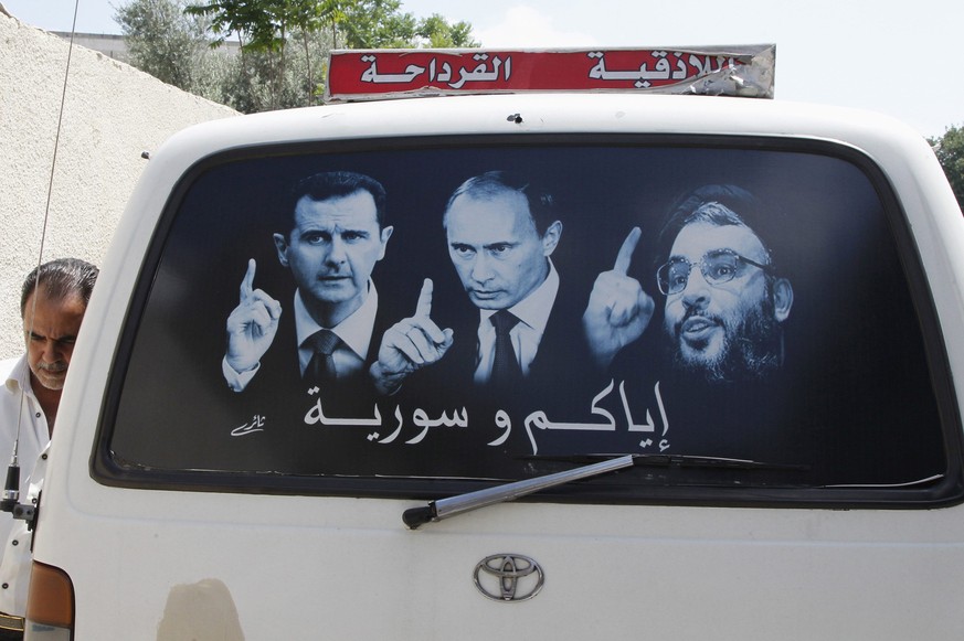 Ein Poster mit Assad (links), Putin (mitte) und dem Libanesischen Hisbollah-Führer Sayyed Hassan Nasrallah auf einem Bus in der Nähe der syrischen Stadt Latakia.