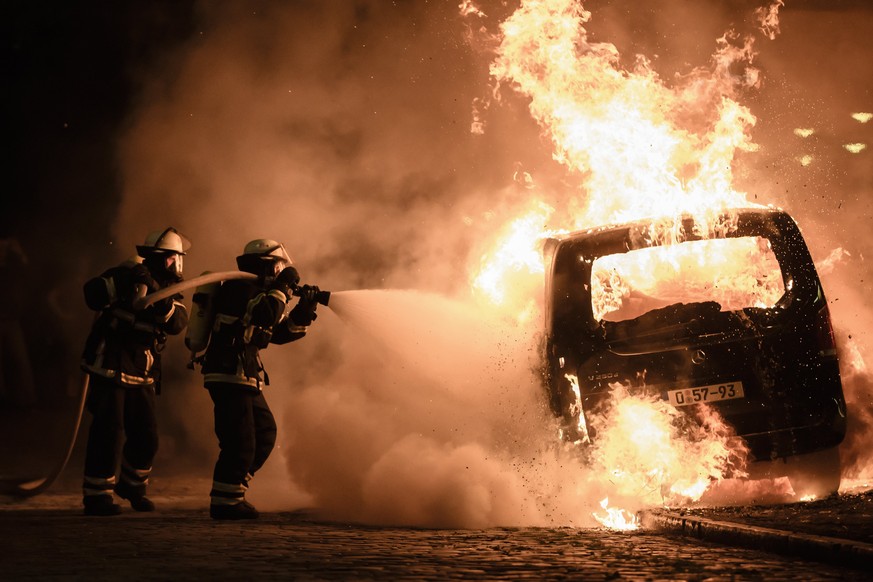 epa06074634 Firefighters extinguish the fire of a burning car during riots at the G20 summit in Hamburg, Germany, 08 July 2017. The G20 Summit (or G-20 or Group of Twenty) is an international forum fo ...