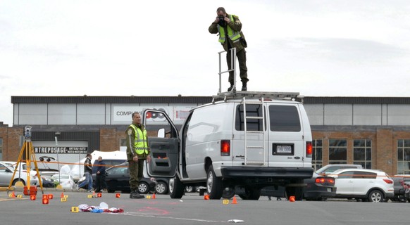 Police investigators take photos at the scene where two soldiers were struck by a car in St-Jean-sur-Richelieu, Quebec on Monday Oct. 20, 2014. One of two soldiers hit by a car died of his injuries ea ...