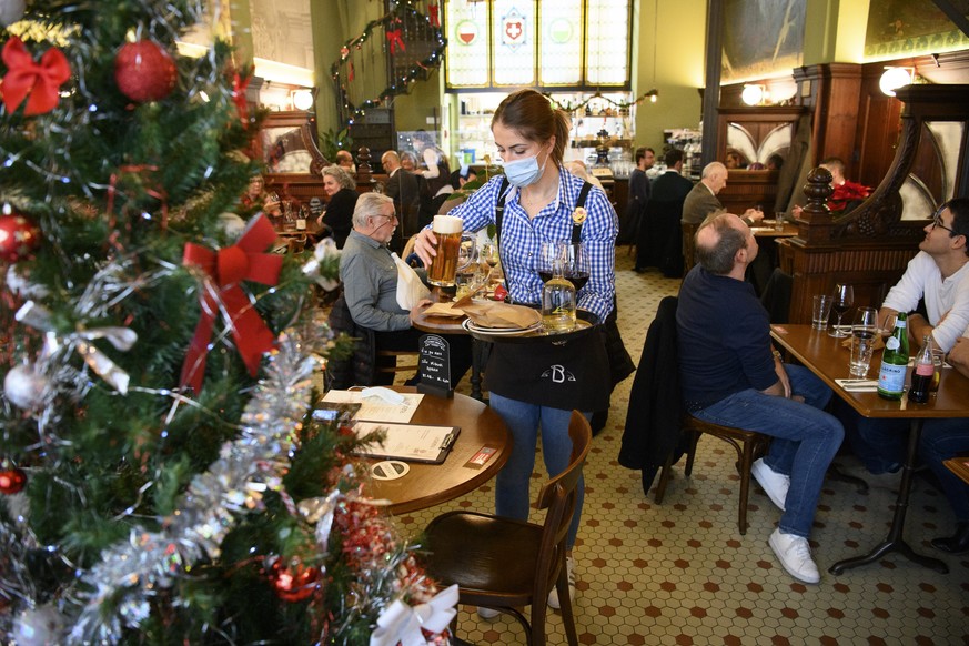 A waiter wearing a face protection mask serves food close to a Christmas tree at the restaurant La Bavaria during the reopening lunch after 5 weeks of closure during the coronavirus disease (COVID-19) ...