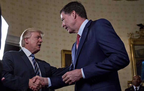 epa05742575 US President Donald J. Trump, center, shakes hands with James Comey, director of the Federal Bureau of Investigation (FBI), during an Inaugural Law Enforcement Officers and First Responder ...