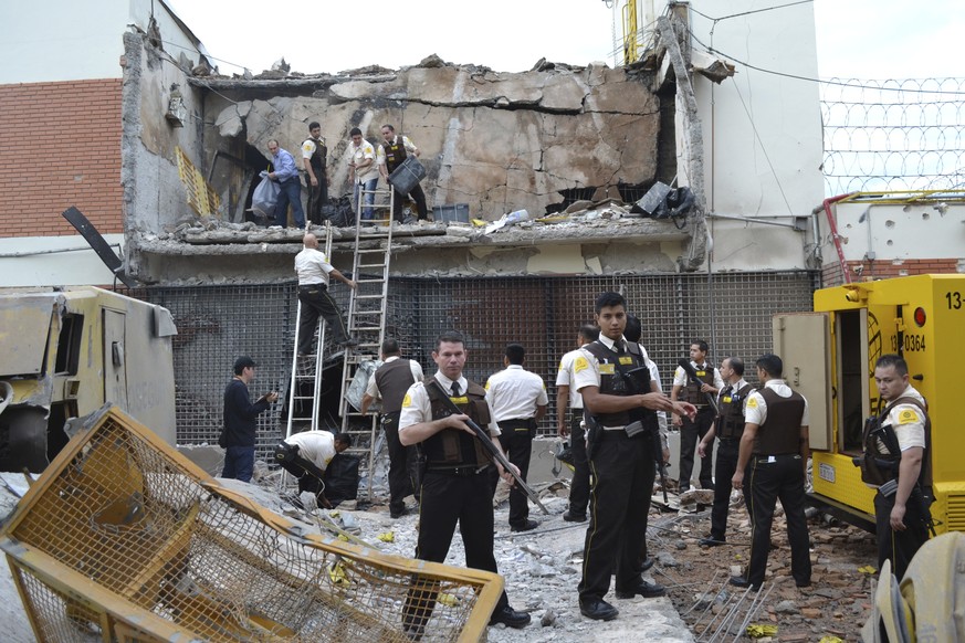 Guards and police inspect a vault that the assailants blew up early morning in Ciudad del Este, Paraguay, Monday, April 24, 2017. Dozens of attackers armed with assault rifles used explosives to blast ...