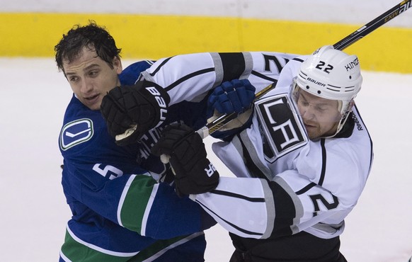 Vancouver Canucks defenseman Luca Sbisa (5) fights for control of the puck with Los Angeles Kings center Trevor Lewis (22) during the third period of an NHL hockey game in Vancouver, British Columbia, ...