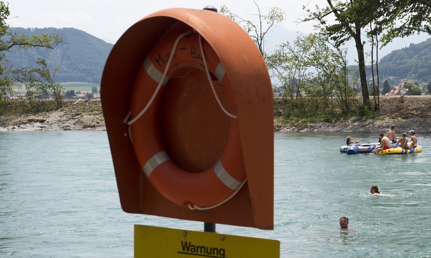 Aareschwimmer und Schlauchbootfahrer geniessen den schoenen Sommertag neben einem Rettungsring und einem Warnschild mit der Aufschrift &quot;Warnung - Baden in der Aare auf eigene Verantwortung&quot;  ...