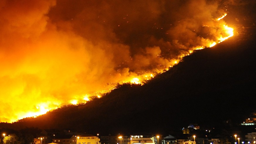 epa06094162 Wildfires in the hills illuminate the scenery near a district of the coastal town of Split, Croatia, in the early morning hours of 18 July 2017. Croatian firemen try to localize and put th ...