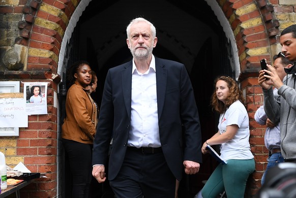 epa06029368 British Labour Party leader Jeremy Corbyn (C) visits St.Clements Church relief centre close to the scene of the fire that broke out at Grenfell Tower, a 24-storey apartment block in North  ...