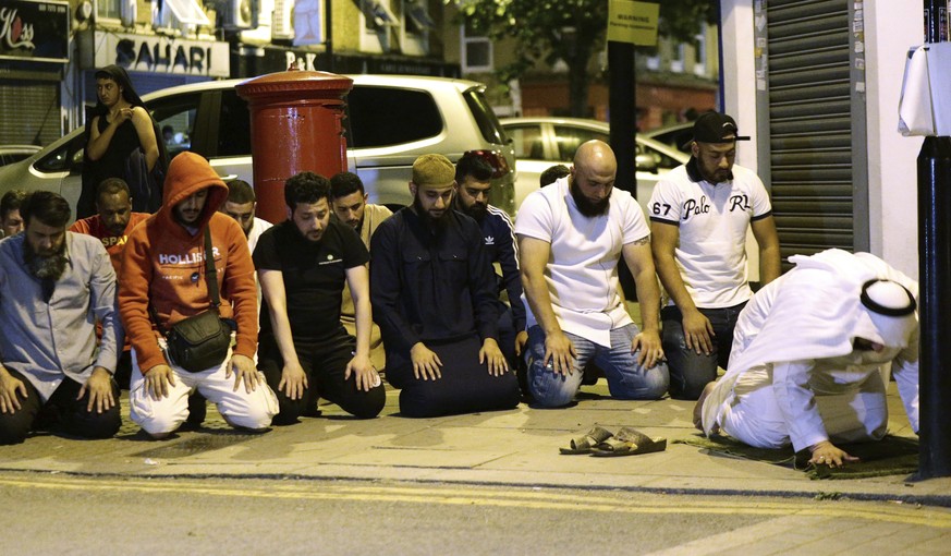 Local people observe prayers at Finsbury Park where a vehicle struck pedestrians in London Monday, June 19, 2017. Police say a vehicle struck pedestrians near a mosque in north London, leaving several ...
