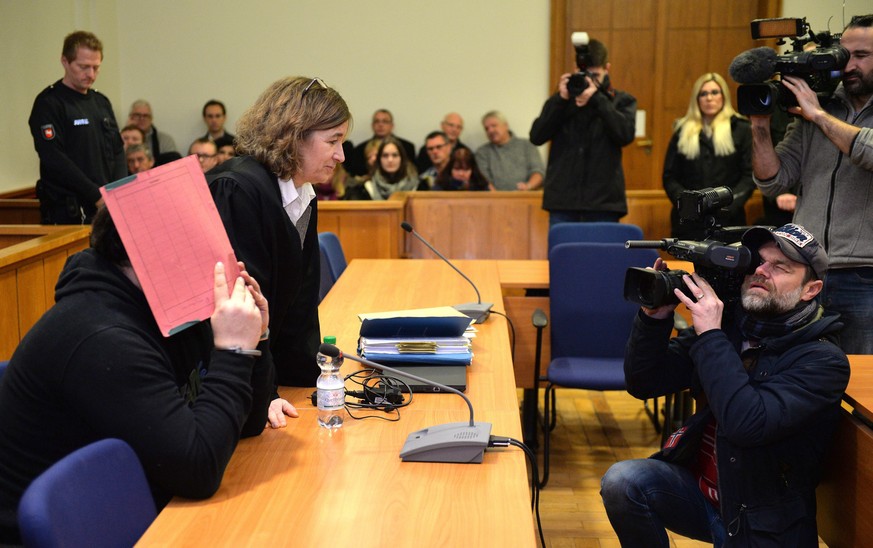 epa04575147 Former nurse Nils H., charged with multiple murders, sits next to his lawyer Ulrike Baumann (2-R) and hides his face with a folder in the district court in Oldenburg, Germany, 22 January 2 ...