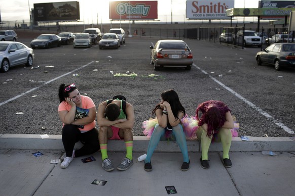 After a long night of partying at the Electric Daisy Carnival, festival goers rest on a curb outside of the Las Vegas Motor Speedway early in the morning on Saturday, June 21, 2014, in Las Vegas. Many ...