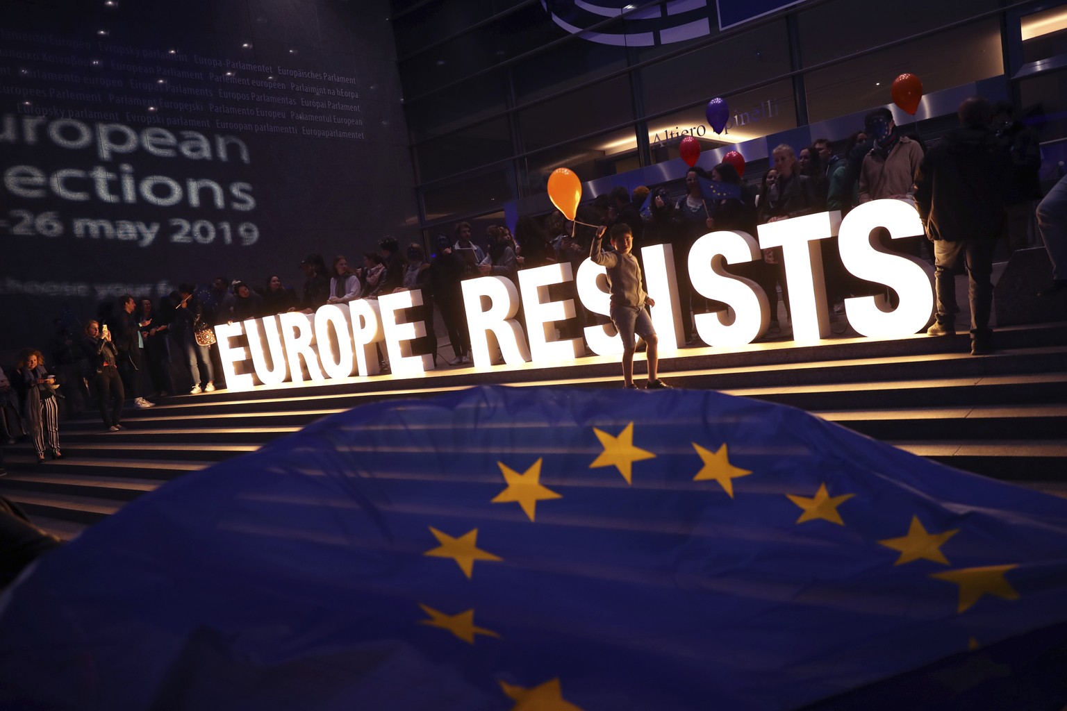 A young boy with a balloon walks by a sign erected by climate activists outside the European Parliament in Brussels, Sunday, May 26, 2019. From Germany and France to Cyprus and Estonia, voters from 21 ...