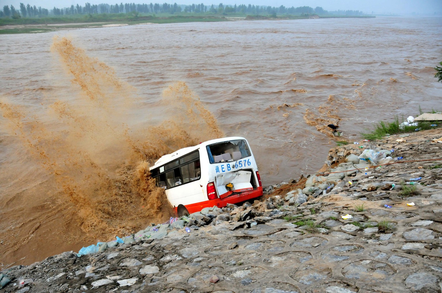 An abandoned bus filled with sand bags is used to build a makeshift dike at a flooded area in Xingtai, Hebei Province, China, July 21, 2016. Picture taken July 21, 2016. REUTERS/Stringer ATTENTION EDI ...