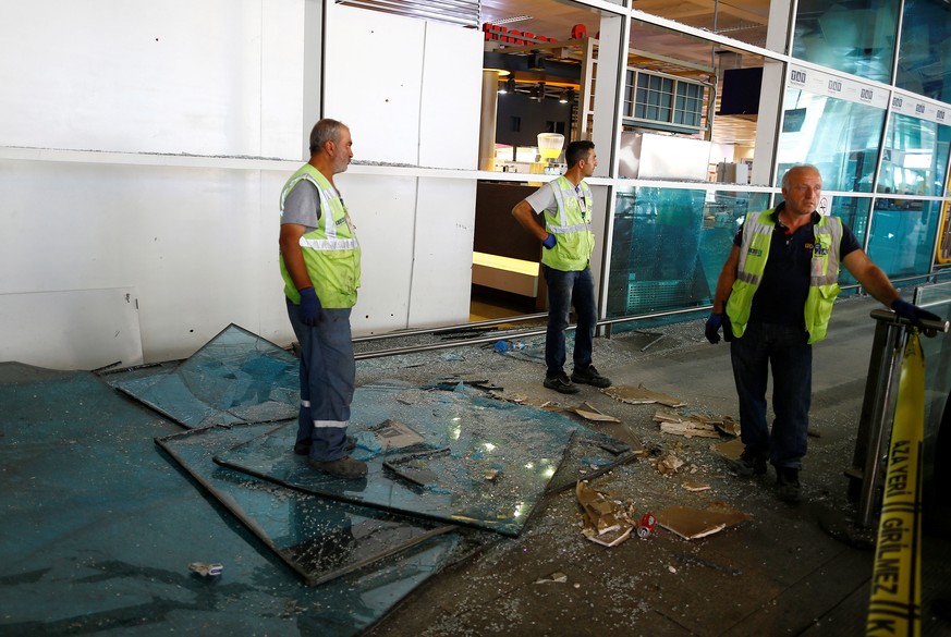 Aufräumarbeiten im Gange: Mitarbeiter der Flughafens räumen beschädigte Scheiben weg.