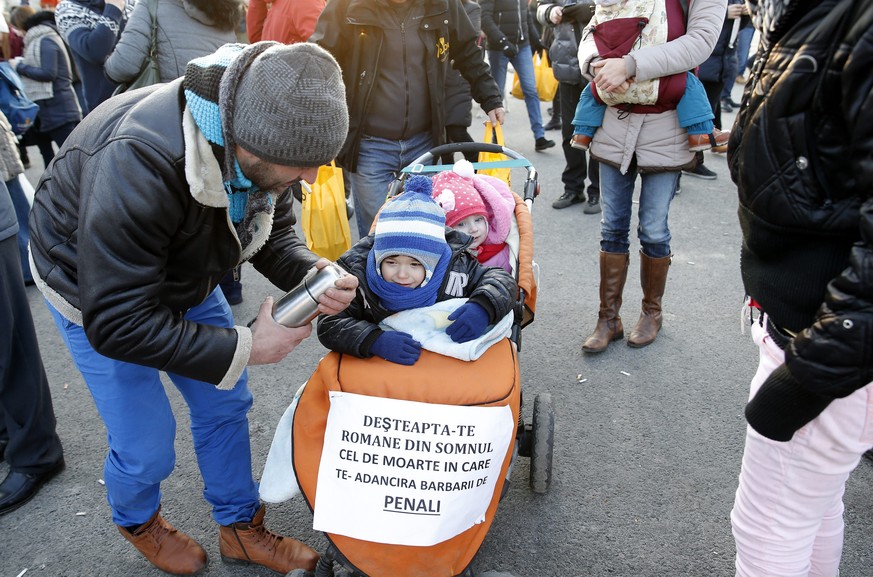 epa05764835 A Romanian man with his his children in a baby carriega and a placard &#039;Wake up Romanian from your deadly sleep, in which you were pushed by the corrupt ones!&#039; during a protest ra ...