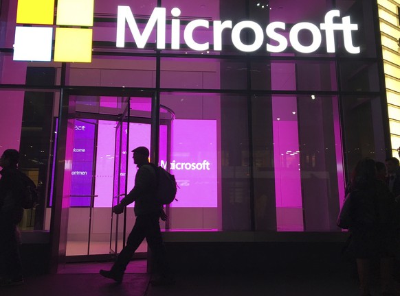 FILE - In this Nov. 10, 2016, file photo, people walk near a Microsoft office in New York. Microsoft Corp. reports earnings, Thursday, April 27, 2017. (AP Photo/Swayne B. Hall, File)