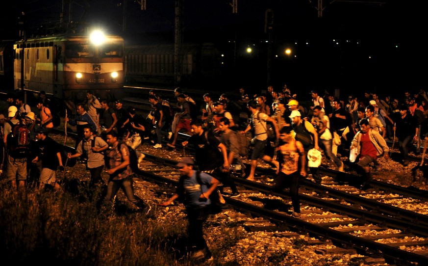 Immigrants from Syria run in front of a train at Tabanovce border crossing between Macedonia and Serbia June 19, 2015. Hungary announced plans on Wednesday to build a four-meter-high fence along its b ...