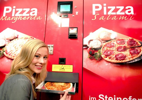 epa02903979 A model takes a pizza out of a vending machine produced by &#039;Pizzomatic&#039; in Cologne, Germany, on 08 September 2011. From 08 to 10 September 2011 &#039;Eu&#039;Vend&#039; fair for  ...